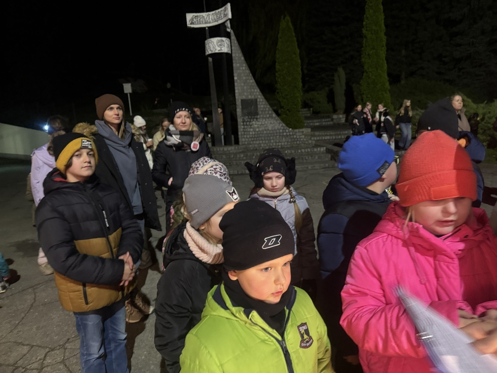 O godzinie 17:00 pod szkołą rozpoczęła się impreza, która zgromadziła około 200 osób. Szkoła została podświetlona na czerwono, co symbolizowało naszą jedność w walce z przemocą. Był to akcent podsumowujący nasze wcześ iej sze  działania w ramach Kampanii Ogólnopolskiej „Dzieciństwo bez Przemocy”. Od października uczniowie uczestniczyli w lekcjach online przygotowanych przez Fundację Dajemy Dzieciom Siłę. Rodzice również zostali objęci wsparciem w postaci webinaru online ww. fudacji.
Uczestnicy mogli wziąć udział w wspólnym śpiewaniu, quizie wiedzy o przemocy oraz tworzeniu „kamieni mocy” – symboli pozytywnej energii i wsparcia. Dodatkowo, w ramach konkursów, przyznano nagrody ufundowane przez Urząd Miejski w Pasłęku.
Ten cudowny czas umilił nam smaczny poczęstunek, w tym grochówka, pizza i ciasta, gorąca kawa i herbatka przygotowany przez panie kucharki i rodziców.
W wydarzeniu uczestniczyli również zaproszeni goście, w tym Burmistrz Pasłęka – pani Elżbieta Wasiuk,  podinspektor KP Pasłęk – pani Agnieszka Bielewicz - Piechowiak oraz przedstawiciel Kuratorium Oświaty w Elblągu – pani Teresa Bednarz, którzy wspierają nasze działania. Ich obecność była dowodem na to, jak ważna jest współpraca lokalnej społeczności w walce z przemocą wobec dzieci. Dziękujemy wszystkim, którzy wzięli udział w tym wyjątkowym dniu oraz przyczynili się do jego organizacji. Razem możemy stworzyć bezpieczne i przyjazne środowisko dla naszych dzieci!
