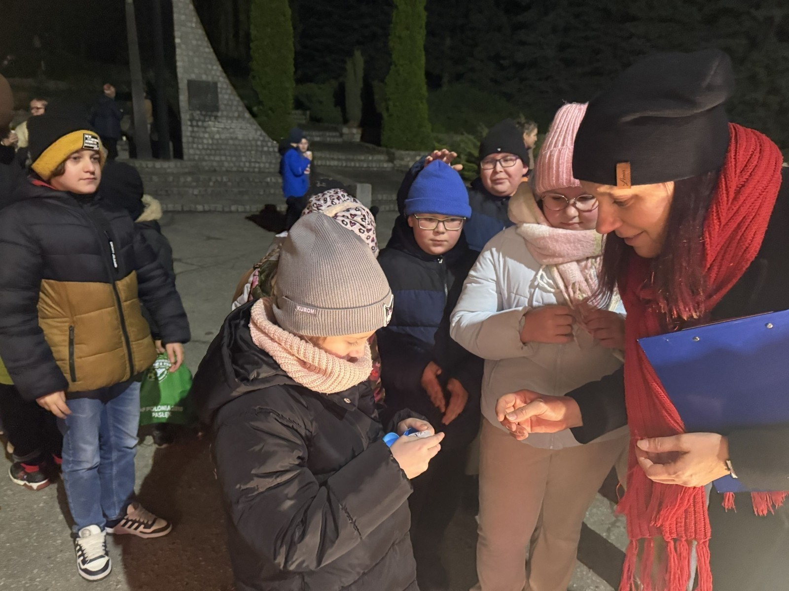 O godzinie 17:00 pod szkołą rozpoczęła się impreza, która zgromadziła około 200 osób. Szkoła została podświetlona na czerwono, co symbolizowało naszą jedność w walce z przemocą. Był to akcent podsumowujący nasze wcześ iej sze  działania w ramach Kampanii Ogólnopolskiej „Dzieciństwo bez Przemocy”. Od października uczniowie uczestniczyli w lekcjach online przygotowanych przez Fundację Dajemy Dzieciom Siłę. Rodzice również zostali objęci wsparciem w postaci webinaru online ww. fudacji.
Uczestnicy mogli wziąć udział w wspólnym śpiewaniu, quizie wiedzy o przemocy oraz tworzeniu „kamieni mocy” – symboli pozytywnej energii i wsparcia. Dodatkowo, w ramach konkursów, przyznano nagrody ufundowane przez Urząd Miejski w Pasłęku.
Ten cudowny czas umilił nam smaczny poczęstunek, w tym grochówka, pizza i ciasta, gorąca kawa i herbatka przygotowany przez panie kucharki i rodziców.
W wydarzeniu uczestniczyli również zaproszeni goście, w tym Burmistrz Pasłęka – pani Elżbieta Wasiuk,  podinspektor KP Pasłęk – pani Agnieszka Bielewicz - Piechowiak oraz przedstawiciel Kuratorium Oświaty w Elblągu – pani Teresa Bednarz, którzy wspierają nasze działania. Ich obecność była dowodem na to, jak ważna jest współpraca lokalnej społeczności w walce z przemocą wobec dzieci. Dziękujemy wszystkim, którzy wzięli udział w tym wyjątkowym dniu oraz przyczynili się do jego organizacji. Razem możemy stworzyć bezpieczne i przyjazne środowisko dla naszych dzieci!
