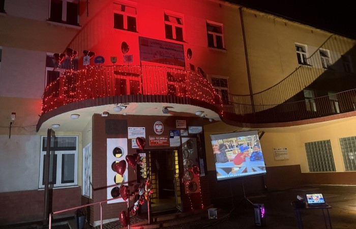 O godzinie 17:00 pod szkołą rozpoczęła się impreza, która zgromadziła około 200 osób. Szkoła została podświetlona na czerwono, co symbolizowało naszą jedność w walce z przemocą. Był to akcent podsumowujący nasze wcześ iej sze  działania w ramach Kampanii Ogólnopolskiej „Dzieciństwo bez Przemocy”. Od października uczniowie uczestniczyli w lekcjach online przygotowanych przez Fundację Dajemy Dzieciom Siłę. Rodzice również zostali objęci wsparciem w postaci webinaru online ww. fudacji.
Uczestnicy mogli wziąć udział w wspólnym śpiewaniu, quizie wiedzy o przemocy oraz tworzeniu „kamieni mocy” – symboli pozytywnej energii i wsparcia. Dodatkowo, w ramach konkursów, przyznano nagrody ufundowane przez Urząd Miejski w Pasłęku.
Ten cudowny czas umilił nam smaczny poczęstunek, w tym grochówka, pizza i ciasta, gorąca kawa i herbatka przygotowany przez panie kucharki i rodziców.
W wydarzeniu uczestniczyli również zaproszeni goście, w tym Burmistrz Pasłęka – pani Elżbieta Wasiuk,  podinspektor KP Pasłęk – pani Agnieszka Bielewicz - Piechowiak oraz przedstawiciel Kuratorium Oświaty w Elblągu – pani Teresa Bednarz, którzy wspierają nasze działania. Ich obecność była dowodem na to, jak ważna jest współpraca lokalnej społeczności w walce z przemocą wobec dzieci. Dziękujemy wszystkim, którzy wzięli udział w tym wyjątkowym dniu oraz przyczynili się do jego organizacji. Razem możemy stworzyć bezpieczne i przyjazne środowisko dla naszych dzieci!
