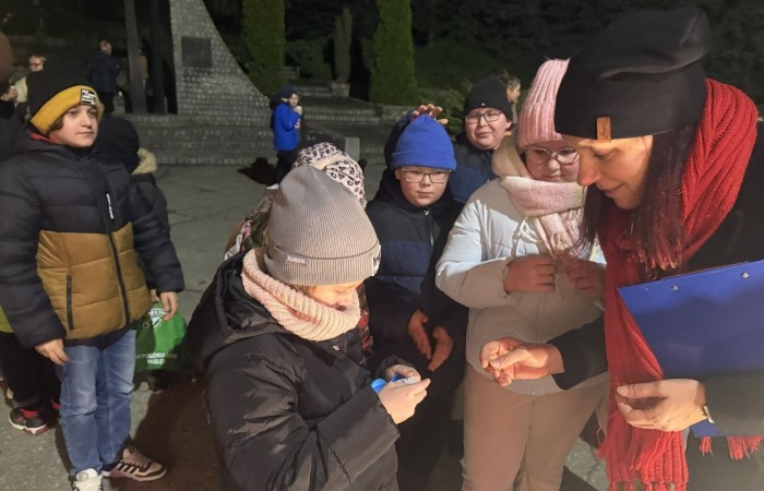 O godzinie 17:00 pod szkołą rozpoczęła się impreza, która zgromadziła około 200 osób. Szkoła została podświetlona na czerwono, co symbolizowało naszą jedność w walce z przemocą. Był to akcent podsumowujący nasze wcześ iej sze  działania w ramach Kampanii Ogólnopolskiej „Dzieciństwo bez Przemocy”. Od października uczniowie uczestniczyli w lekcjach online przygotowanych przez Fundację Dajemy Dzieciom Siłę. Rodzice również zostali objęci wsparciem w postaci webinaru online ww. fudacji.
Uczestnicy mogli wziąć udział w wspólnym śpiewaniu, quizie wiedzy o przemocy oraz tworzeniu „kamieni mocy” – symboli pozytywnej energii i wsparcia. Dodatkowo, w ramach konkursów, przyznano nagrody ufundowane przez Urząd Miejski w Pasłęku.
Ten cudowny czas umilił nam smaczny poczęstunek, w tym grochówka, pizza i ciasta, gorąca kawa i herbatka przygotowany przez panie kucharki i rodziców.
W wydarzeniu uczestniczyli również zaproszeni goście, w tym Burmistrz Pasłęka – pani Elżbieta Wasiuk,  podinspektor KP Pasłęk – pani Agnieszka Bielewicz - Piechowiak oraz przedstawiciel Kuratorium Oświaty w Elblągu – pani Teresa Bednarz, którzy wspierają nasze działania. Ich obecność była dowodem na to, jak ważna jest współpraca lokalnej społeczności w walce z przemocą wobec dzieci. Dziękujemy wszystkim, którzy wzięli udział w tym wyjątkowym dniu oraz przyczynili się do jego organizacji. Razem możemy stworzyć bezpieczne i przyjazne środowisko dla naszych dzieci!
